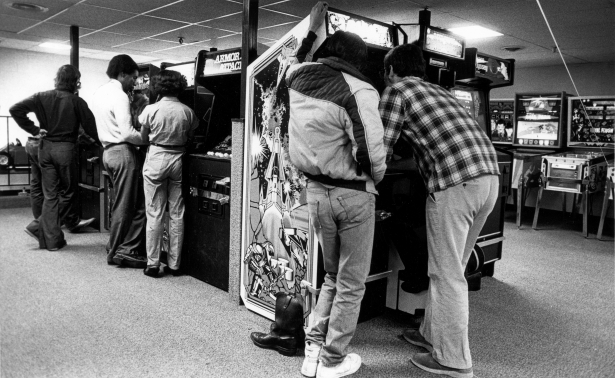 Gentlemen hovering over arcade games at Celebrity Sports Center