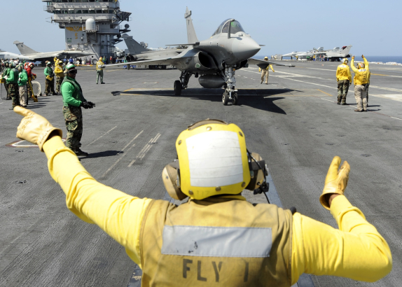 Aircraft carrier USS Theodore Roosevelt (CVN 71) deck crew guides a fighter jet, 