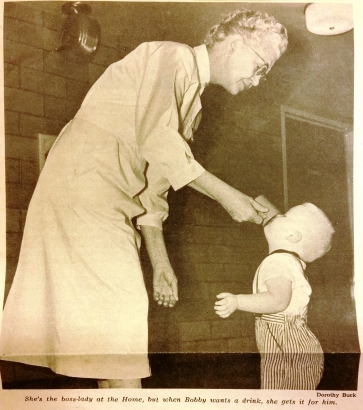 Image of nurse holding cup with child drinking