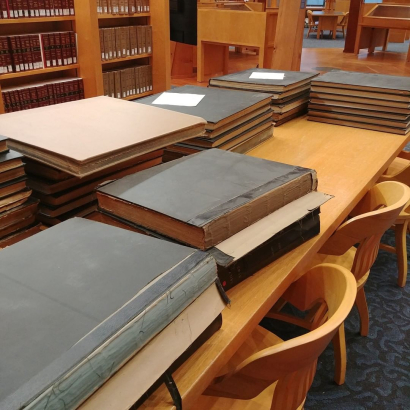 Stacks of large volumes on a wooden table
