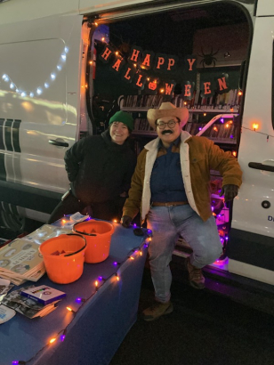 DPL Staff handing out free AA.NH/PI Community Cookbooks at the Denver Far East Center Trunk or Treat event in 2023.