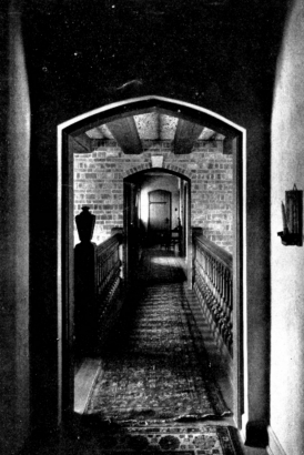 View of a bridged hallway from a doorway looking towards a second doorway.