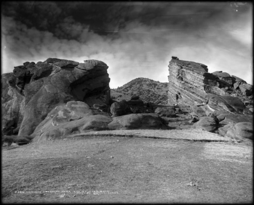 View of Creation Park (Red Rocks Park) in Morrison, Colorado; sandstone rocks forming natural amphitheater are shown, with bleachers at top; Mt. Morrison in distance with funicular railway track.