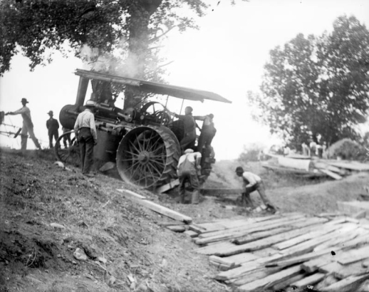 View of men driving a steam tractor up an embankment, in Denver, Colorado.