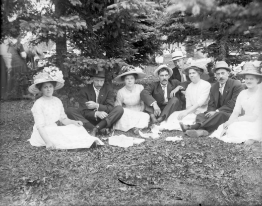 Outdoor portrait of men and women in a Denver, Colorado, park; costume includes large hats with flowers.