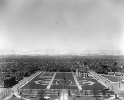 View west from dome of State Capitol Building over Civic Center, Denver, Colorado, shows the cruciform plan located between West Fourteenth (14th) Avenue and West Colfax. The Denver Public Library and the United States Mint show prominently among buildings that later would be raised for Civic Center exspansion. Signs on Cleveland Place read: "The Manualo," "The Baldwin Piano Co." and "Thurney Auto Co."