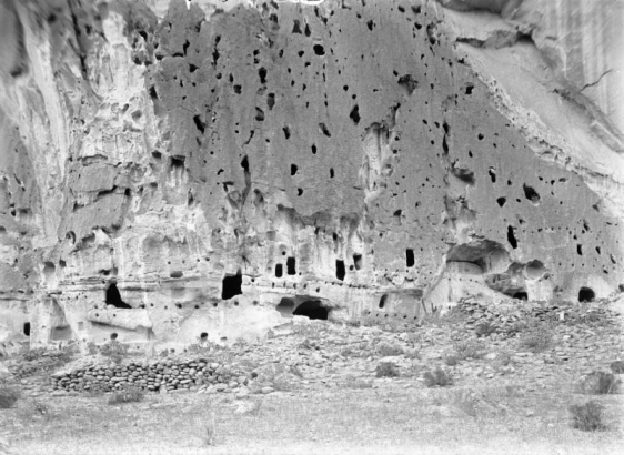 Eroded windows and bird nest holes show in the soft volcanic rock of a verticle tuff cliffside, Frijoles Canyon, Bandelier National Monument, New Mexico.