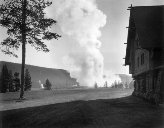 View along the side of rustic 1904 Old Faithful Inn over a steaming Upper Geyser Basin, Yellowstone National Park, Wyoming.