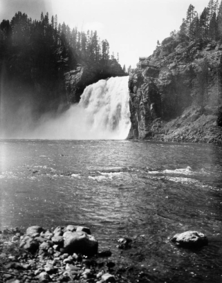 Upper Falls of the Yellowstone River, Yellowstone National Park, Wyoming, shows the raging waterfall with a wooden stairway on a rocky cliff leading to a vantage point.