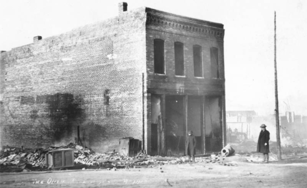 Fire-gutted exterior view of two-story, flat roof, single story brick commercial building, Bennett Avenue, caused by second fire of April 29, 1896, Cripple Creek, Colorado; decorative cornice.