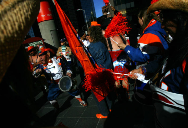 A man know as Rocky the Leprechaun, left, fires up over one hundred fans before they marched up and down the 16th Street Mall during a Kool 105 Parade to support the Denver Broncos in their game against the New England Patriots Saturday which will be t...