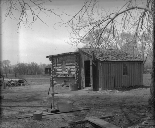 Old Olsen's log and plank shack residence Petersburg (later Englewood), Arapahoe County, Colorado, includes a hand pump and washtub.