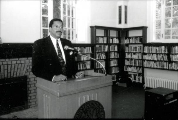 Denver Mayor Wellington Webb stands behind a podium, speaking during the Woodbury Branch library re-opening press conference in Denver, Colorado.