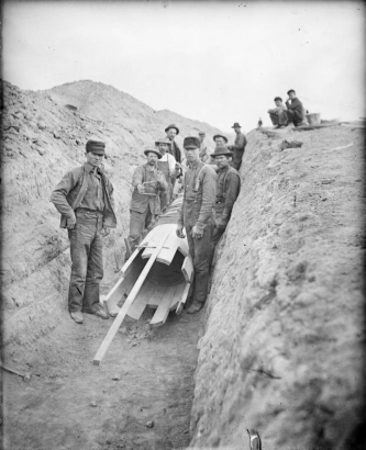Workmen pose in a trench near a wooden pipe form in Denver, Colorado.