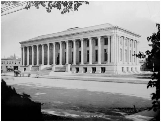 Exterior view of the Denver Public Library, at Civic Center, Bannock and Colfax, Denver, Colorado, dedicated in 1910; view across Colfax shows horse-drawn carriage, bicycles and automobile parked at curb.