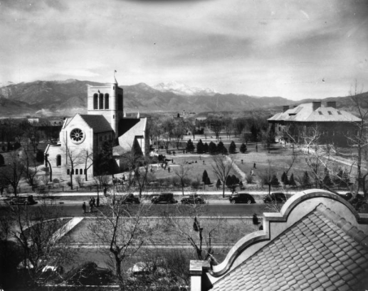 View of Colorado College, Colorado Springs, El Paso County, Colorado, from the Lennox house roof; shows Shove Memorial Chapel (gift of Eugene P. Shove). John Gray's design includes a square belltower, turret, and rosette window. Cars line Nevada Avenue; Palmer Hall edges lawn.