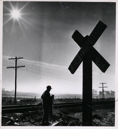 A farmer stands next to the battered railroad crossing sign four days after the tragedy. The crossing had no flashing lights or automatic arms, just two road signs to warn motorists. (BILL PEERY/ROCKY MOUNTAIN NEWS/1961)