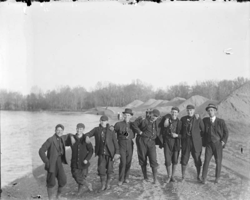 Outdoor portrait of a group of men near the South Platte River in Denver, Colorado. Some of the men wear baseball uniforms that read: "[?]land".