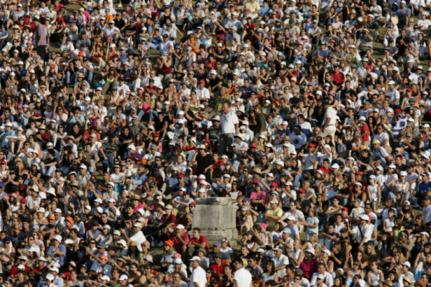 (OLYMPIA, GREECE, AUGUST 18, 2004) Fans sit along the grass banks of the Ancient Stadium in Olympia surrounding a remanding pillar as they watch Olympians pefrom in the shot put competition in the 2004 Athens Summer Olympic Games held in Olympia, Greec...