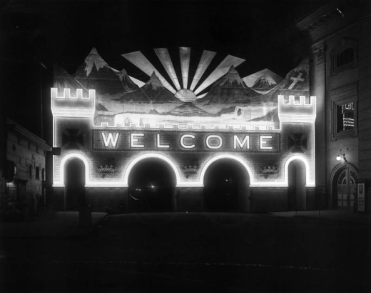 Night view of the illumintated archway on Champa Street and Fourteenth, for the Knights Templar 32nd Triennial Conclave, Denver, Colorado. "Electric sunset and Mt. (Mount) of the Holy Cross. Over 60,000 candle power required to illuminate This electric painting. Rays of the sun  and lighting effects on the mountain peaks are obtained from twelve search  lights."