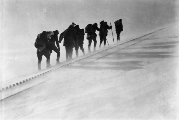 Snow blows by seven members of the AdAmAn Club as they make their way up a steep incline of the Pikes Peak Cog Railway tracks on Pikes Pike, an annual mountaineering trek to the top of the 14,110 foot mountain to set off fireworks on New Years Eve, Colorado Springs, El Paso County, Colorado. They carry backpacks, walking sticks and a camera tripod.
