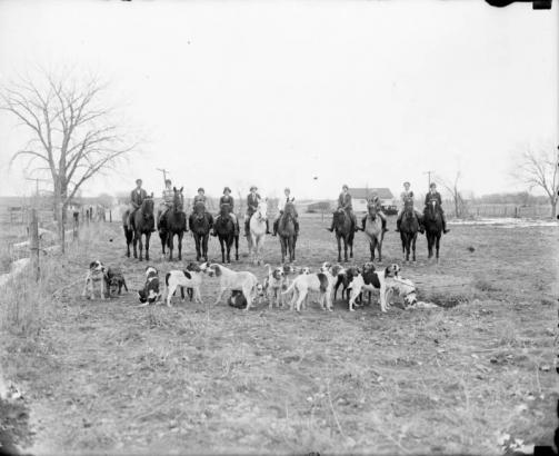 Women pose on horseback by a pack of hunting dogs in Colorado.