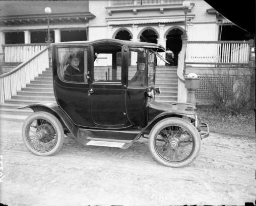 Mr. and Mrs. Harry and Addie Mellon Rhoads, parents of Harry M. Rhoads sit inside an electric automobile in front of City Park pavilion, Denver, Colorado.