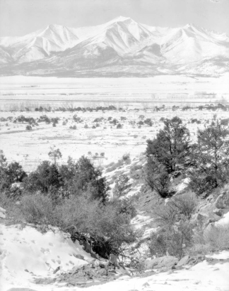 View of fields, snow, and mountains, possibly in Colorado.