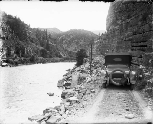 View of a car on the Taylor State Road, in Glenwood Canyon (Eagle or Garfield County) Colorado; Denver and Rio Grande Railroad tracks are across the Colorado River.