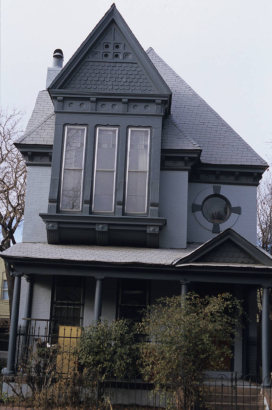 View of 2525 Champa Street in the Five Points neighborhood of Denver, Colorado. The residence is listed on the National Register of Historic Places as a contributing resource to the Curtis Park-Champa Street Historic District. The two-story brick Queen Anne house (c. 1885) has a full porch with a pediment above the entry, a bay with a pediment, cornice and fishscale shingles. There is an oriel window on the second floor and an oculus above the porch pediment.