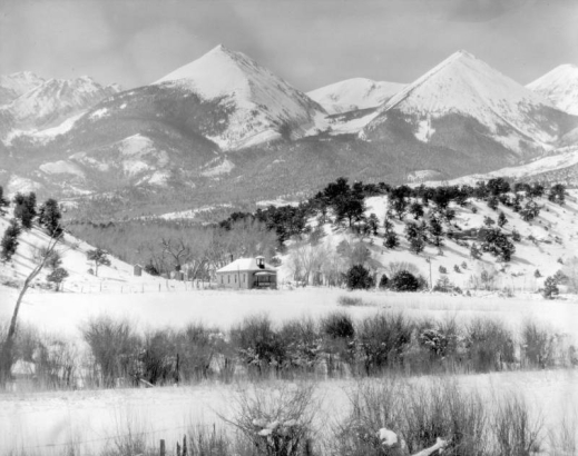 View of Howard (Fremont County), Colorado; shows the Stout School (District 13), later the Howard Volunteer Fire Department, snow, and Twin Sisters Peaks.