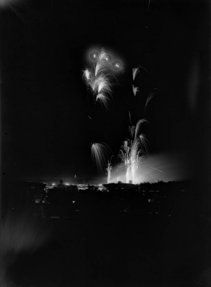 Night view of fireworks exploding over Denver, Colorado, as seen from City Park Lake. Colorado State Capitol dome in distance.