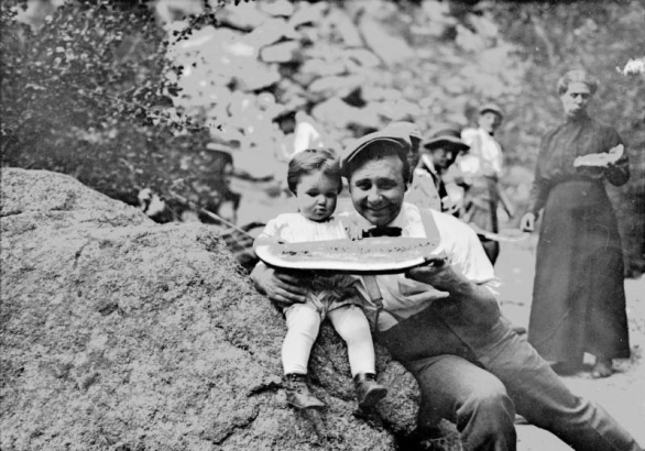 Harry Rhoads holds a piece of watermelon with his daughter Mary Elizabeth (Mitzi) at a gathering in Colorado.