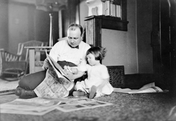 Harry Rhoads sits reading the comics with his daughter Mary Elizabeth (Mitzi), Denver, Colorado.