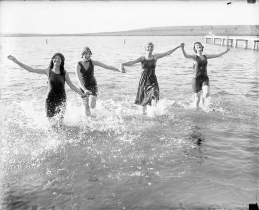 Women laugh and splash in a lake.