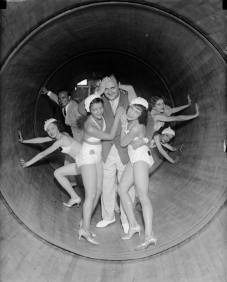 A man poses with women dancers in matching costumes and shoes inside a revolving tube ride at Lakeside Amusement Park in Denver, Colorado.
