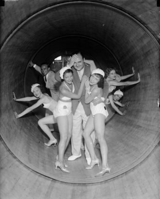 A man poses with women dancers in matching costumes and shoes inside a revolving tube ride at Lakeside Amusement Park in Denver, Colorado.