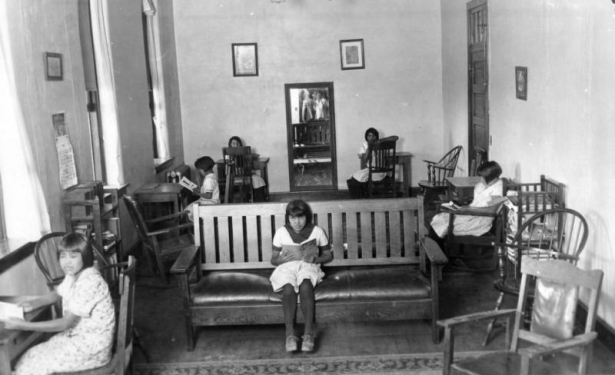 Native American Ute girls pose at wooden desks and a sofa reading books inside their dorm, Southern Ute Agency school, Ignacio, La Plata County, Colorado.