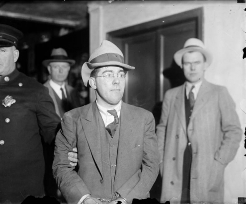 An unidentified man in handcuffs is escorted by a police officer, probably in Denver, Colorado.