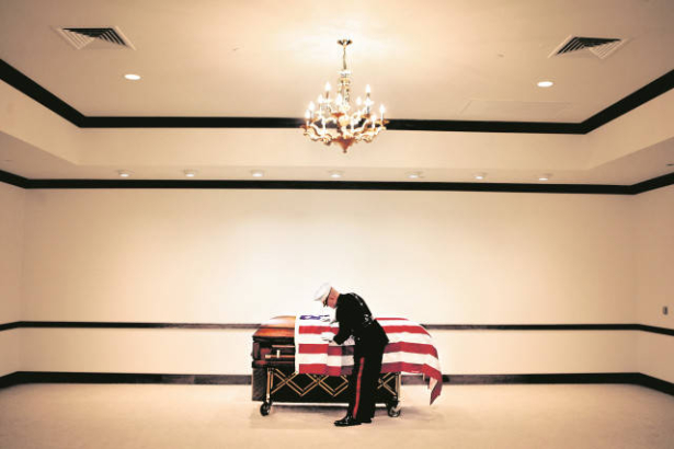 Major Steve Beck folds back the flag while preparing to open James Cathey's casket.