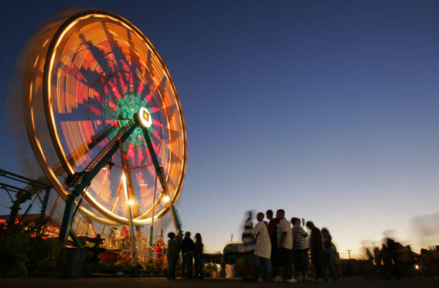 Lights glow in a time lapse photo of the Ferris Wheel as fairgoers wait beneath it for a turn on the first day of the Colorado State Fair in Publo, Colo., on Friday, August 24, 2007. The Midway is where the the rides and games are at and is popular, es...