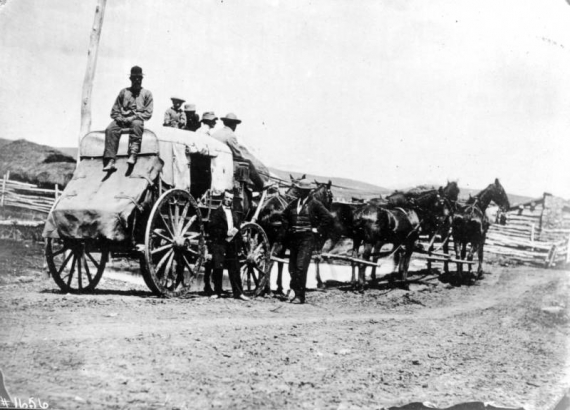 Men pose on a horse-drawn stagecoach that belongs to Ben Holladay's Overland Stage Company at Kimball's possibly in Colorado.