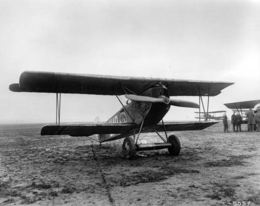 View of a Fokker D-VII biplane with a 185 horsepower BMW engine; men and other airplanes are to the side.