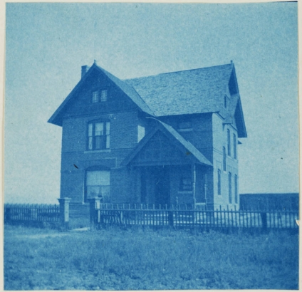 View of a residence, possibly belonging to the Ingersoll family, Denver, Colorado. It is a three story brick and wood structure with intersecting gables and open front porch.