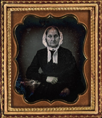 Studio portrait (sitting) of a woman. She wears a kerchief on her head.