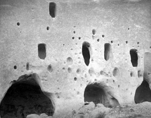 Close-up view of the Puye Cliffs, Native American (Tewa) tuff dwellings, at Puye Cliff Dwellings, Santa Clara Pueblo, New Mexico. The cliffs have arched doorways that stand underneath holes for vigas.