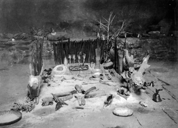 Interior view of a Native American Hopi Pueblo kiva, Third Mesa, Arizona, shows an altar set for a sacred ceremony with fetishes, corn cobs, animal skulls, baskets, bells, feathers and pottery.