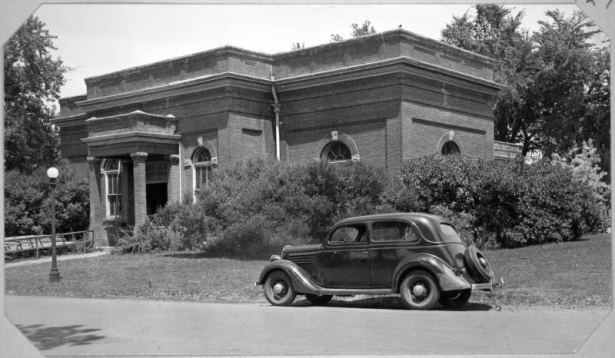 View of the powerhouse in City Park, Denver, Colorado. An automobile is parked nearby.