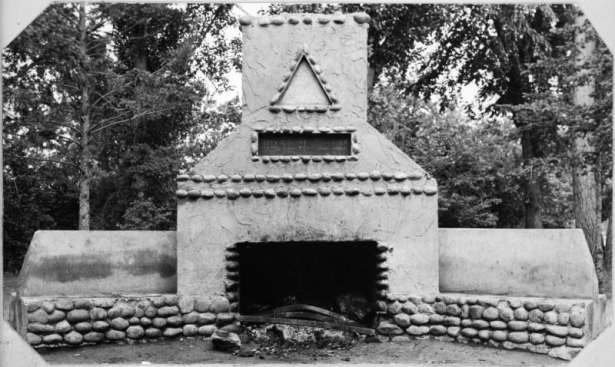View of a stone and cement grill and chimney in Washington Park, Denver, Colorado. A sign above on the chimney reads: "Presented To The City & County of Denver By The Denver Campfire Girls".