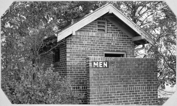 View of a brick restroom building at Sloan's Lake Park in Denver, Colorado. A sign painted on a brick dividing wall reads: "Men".